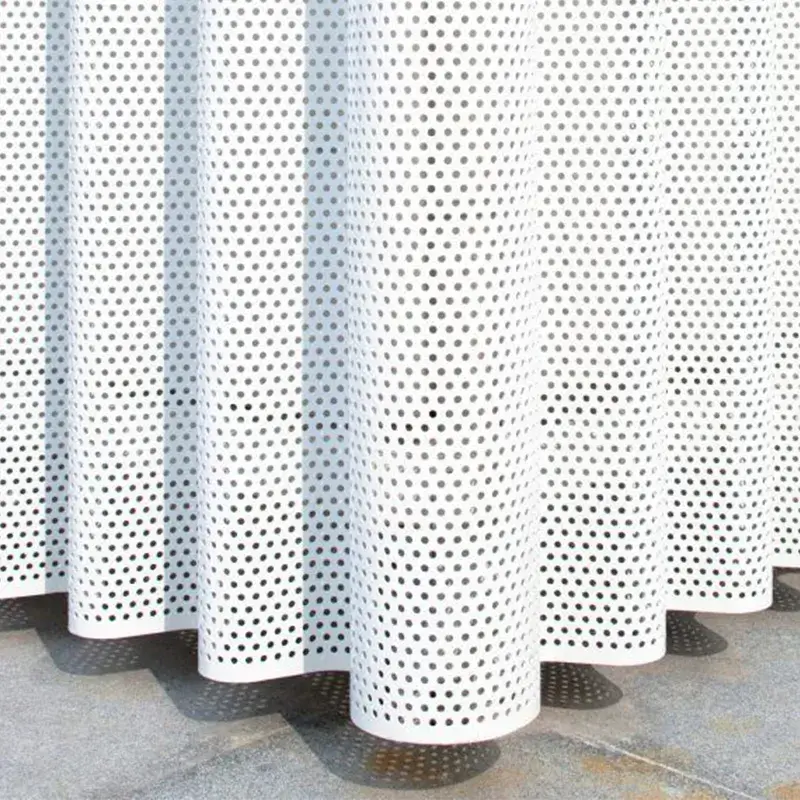 White aluminum perforated panels with circular cut-outs, curved to form a wave-like structure. The design highlights the flexibility and aesthetic appeal of perforated panels in architectural applications.