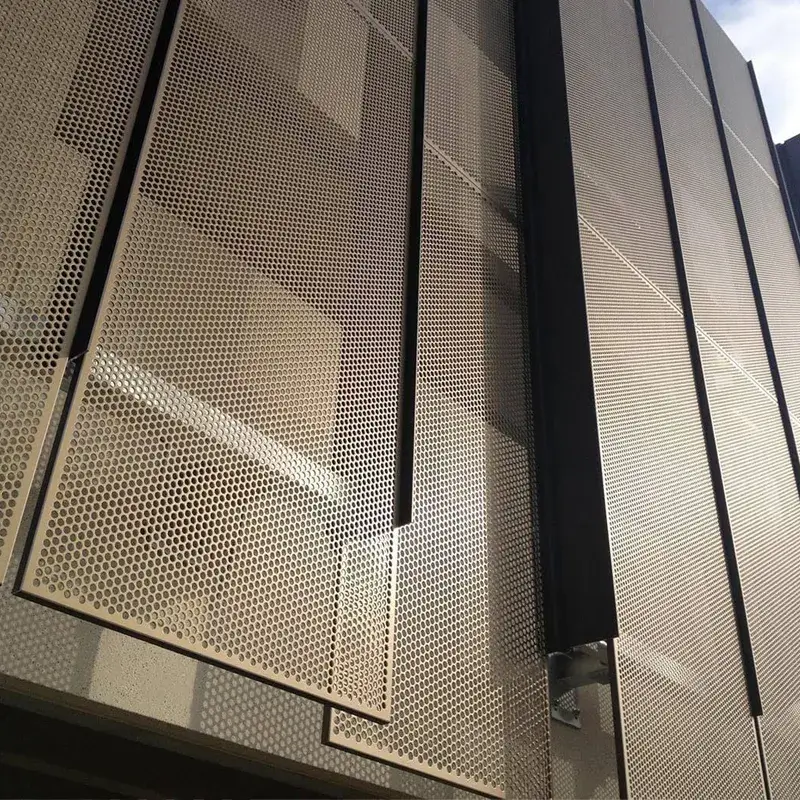 A close-up view of aluminum perforated panels on a building's exterior facade. The panels have a modern design with round perforations, providing a sleek and contemporary look.