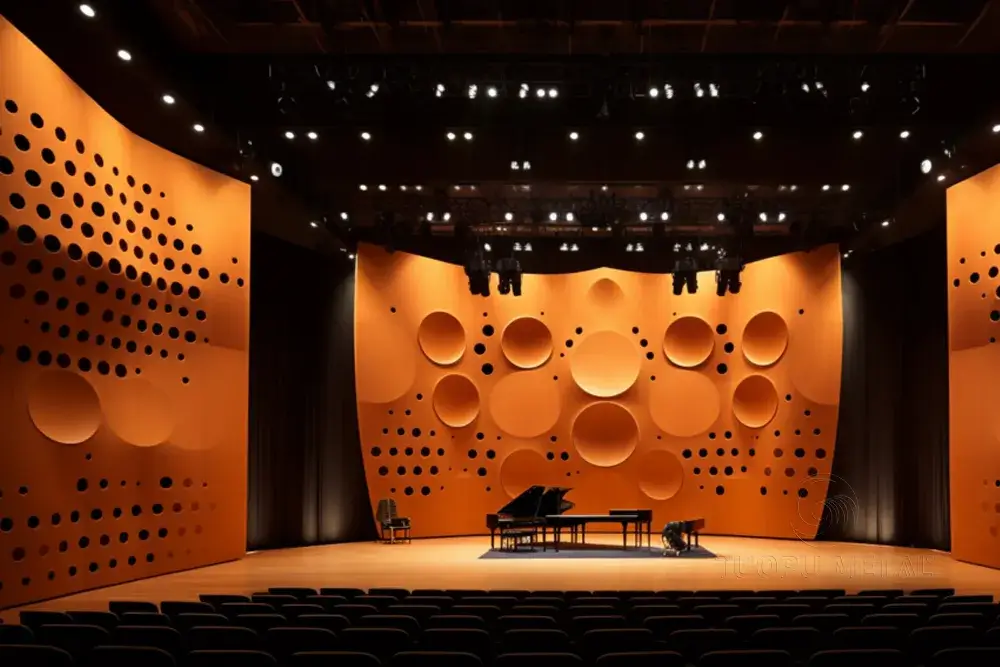 Inside a concert hall, the walls are made of perforated aluminum panels of varying sizes.